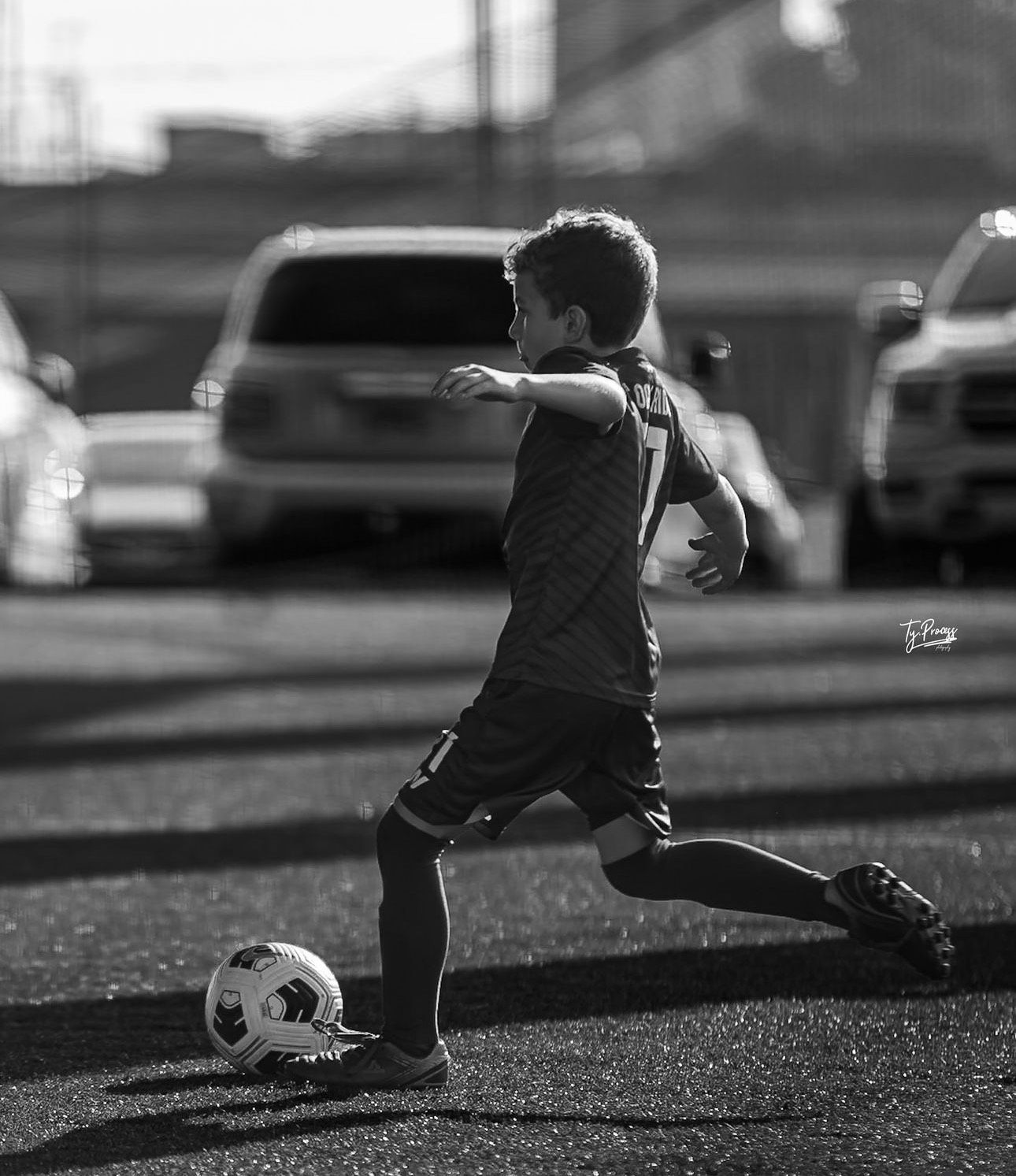 A young boy is kicking a soccer ball on a field.