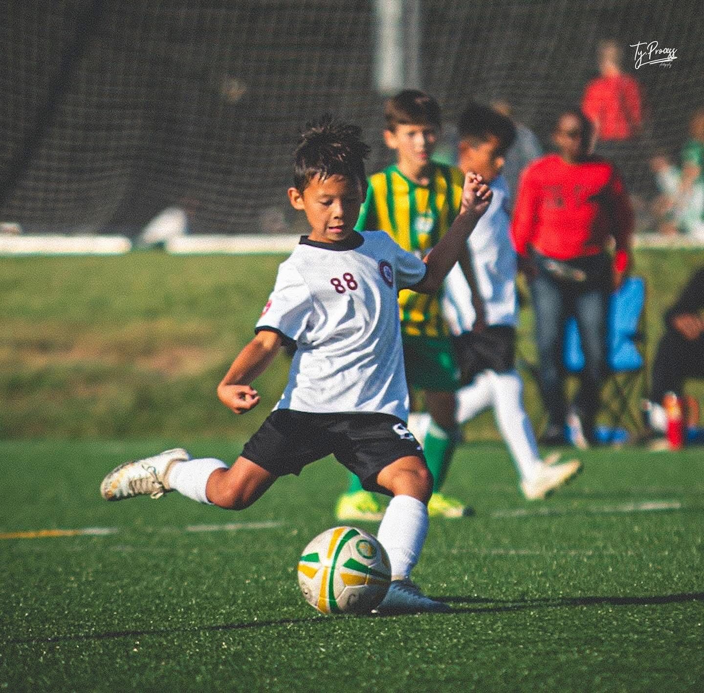 A young SCOR girl is kicking a soccer ball on a field