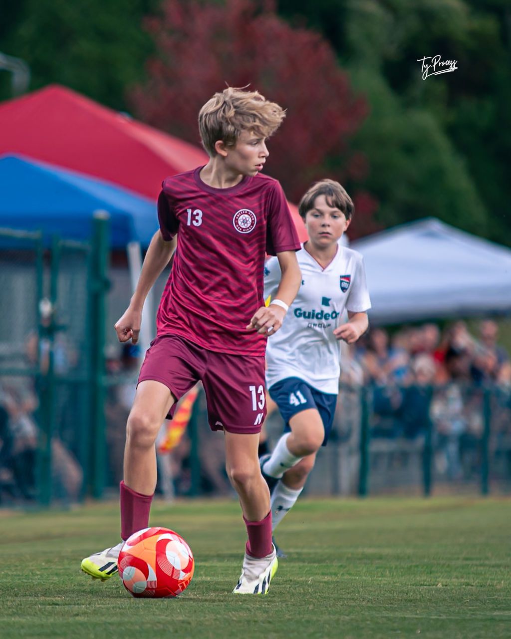 Two young boys are playing soccer on a field.