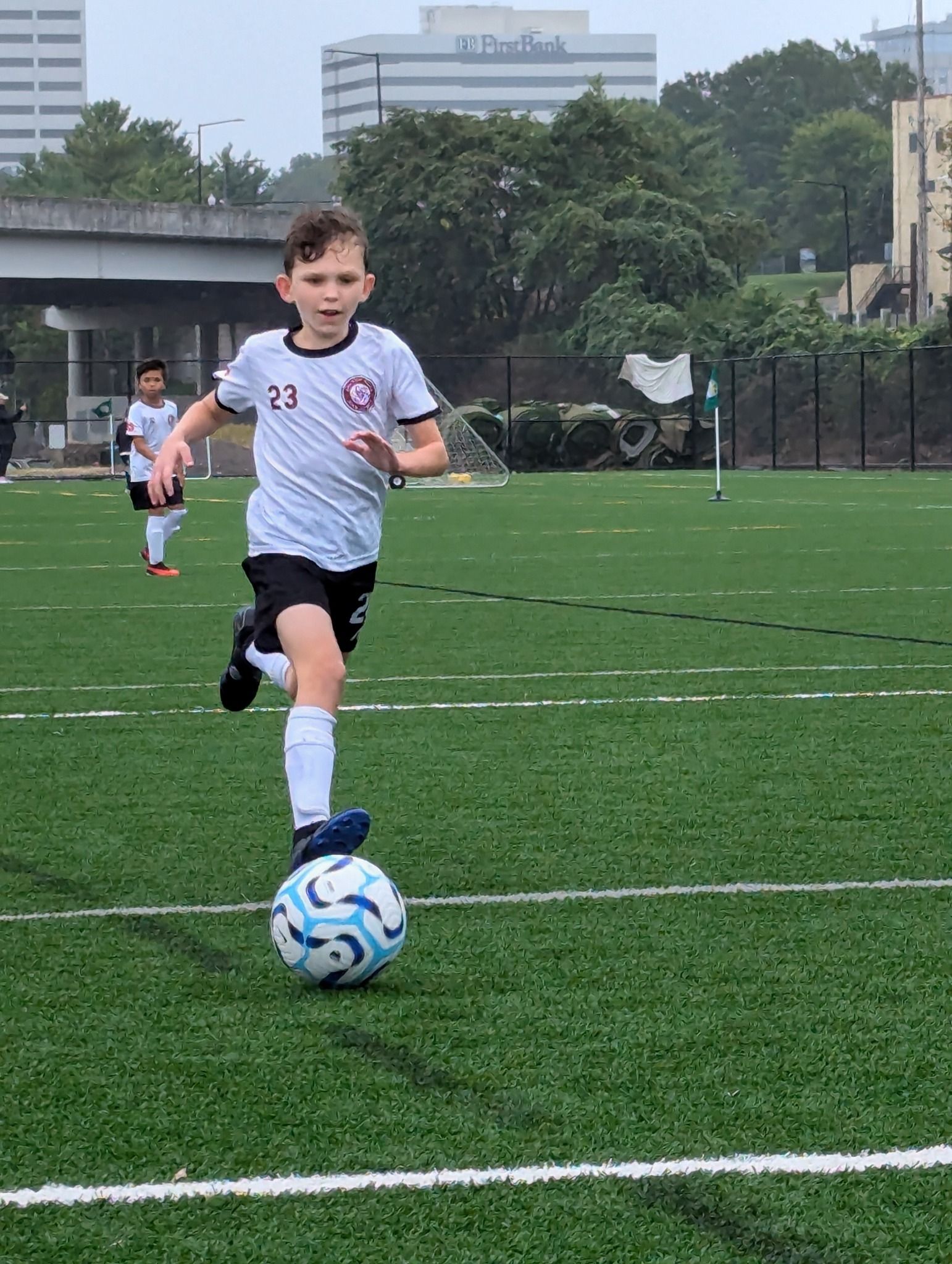 A young boy is kicking a soccer ball on a field.
