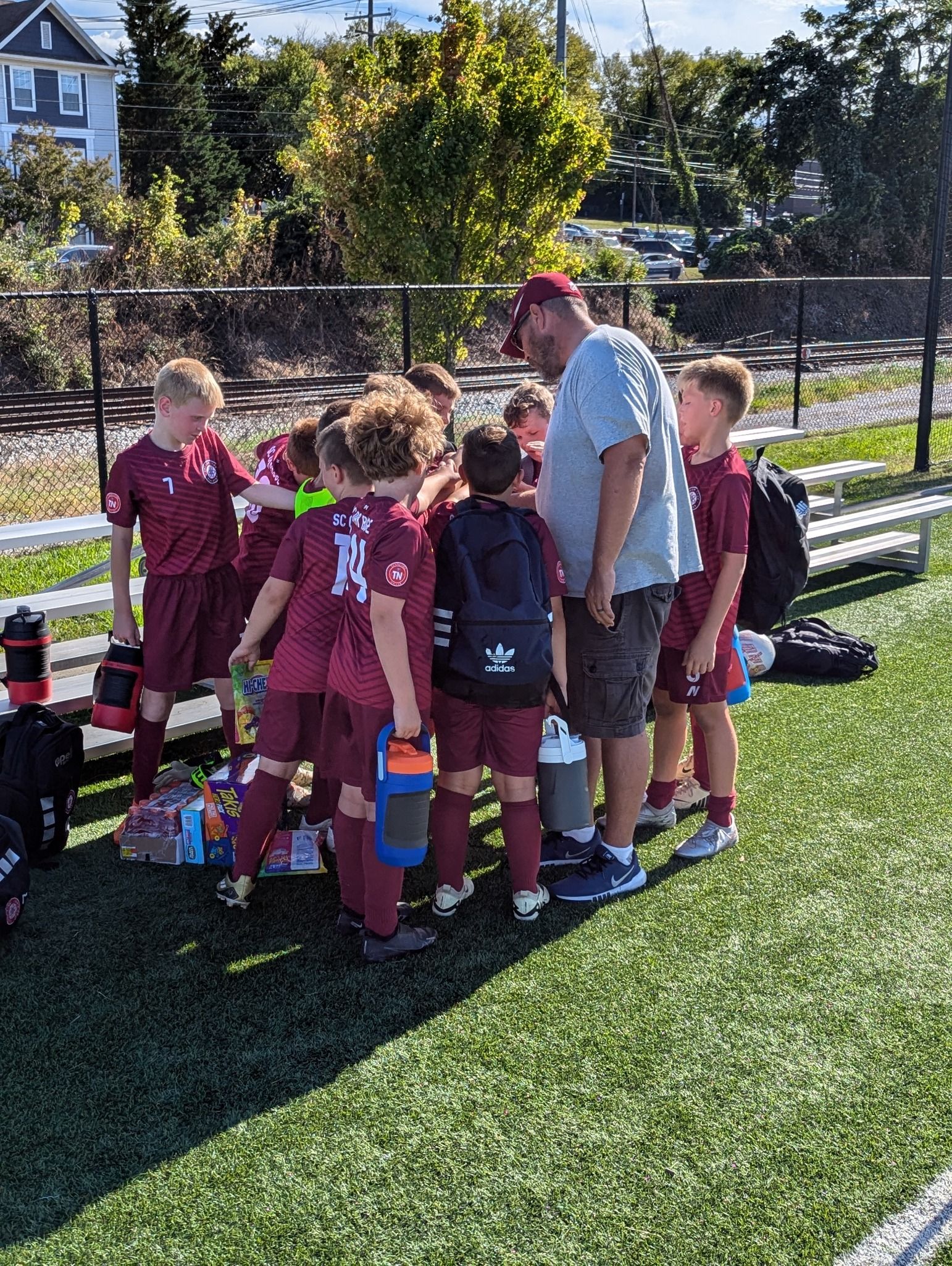 A group of young boys are huddled together on a soccer field.