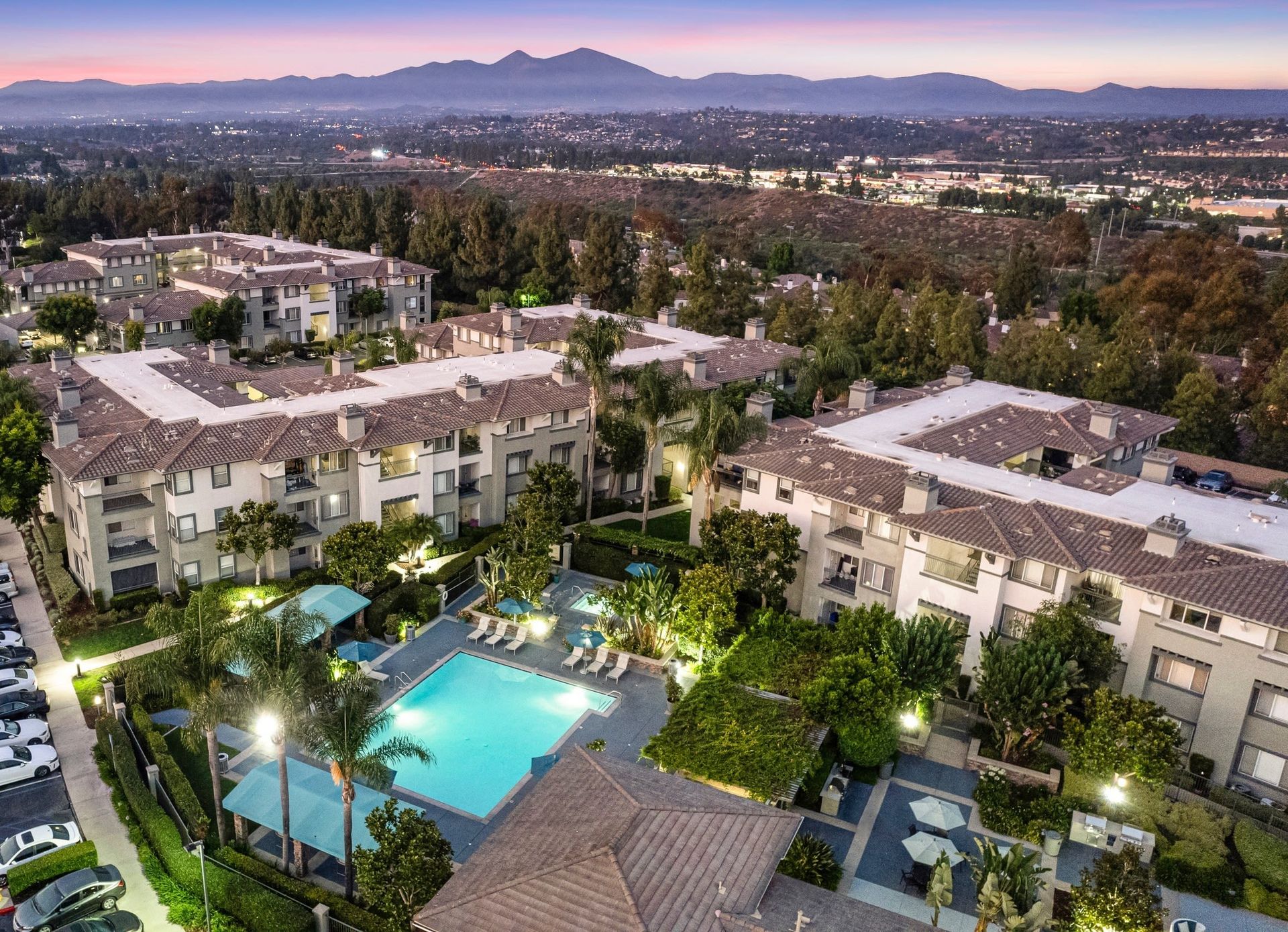 Aerial view of a multi-building apartment complex with a central pool and landscaped grounds.