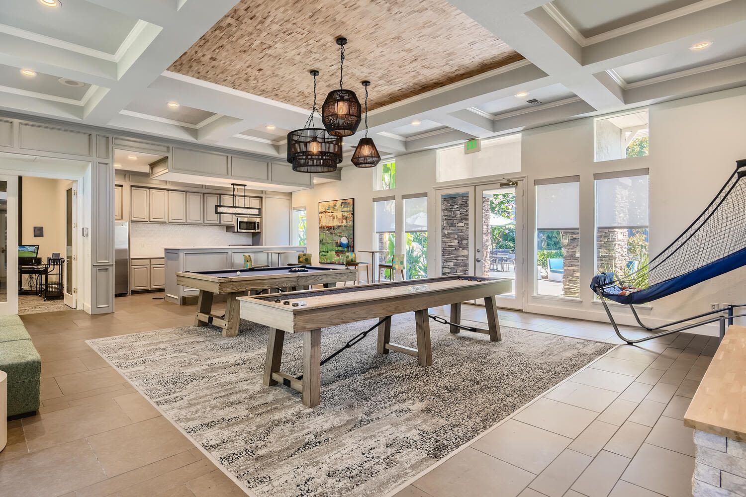 Interior of a community clubhouse with billiards tables, a kitchenette, and lounge seating.