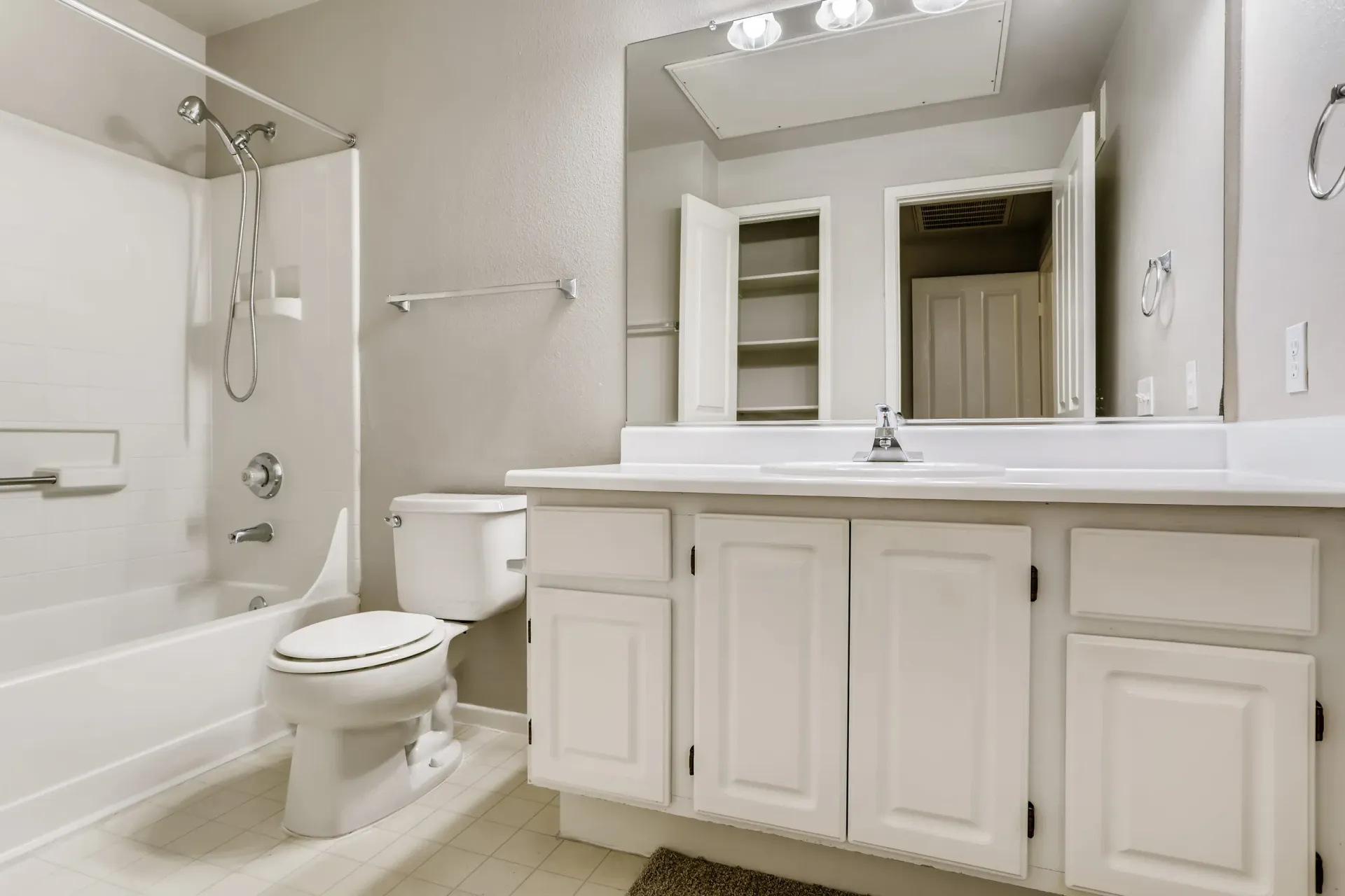 White bathroom with a tub/shower combo, toilet, and a wide vanity.