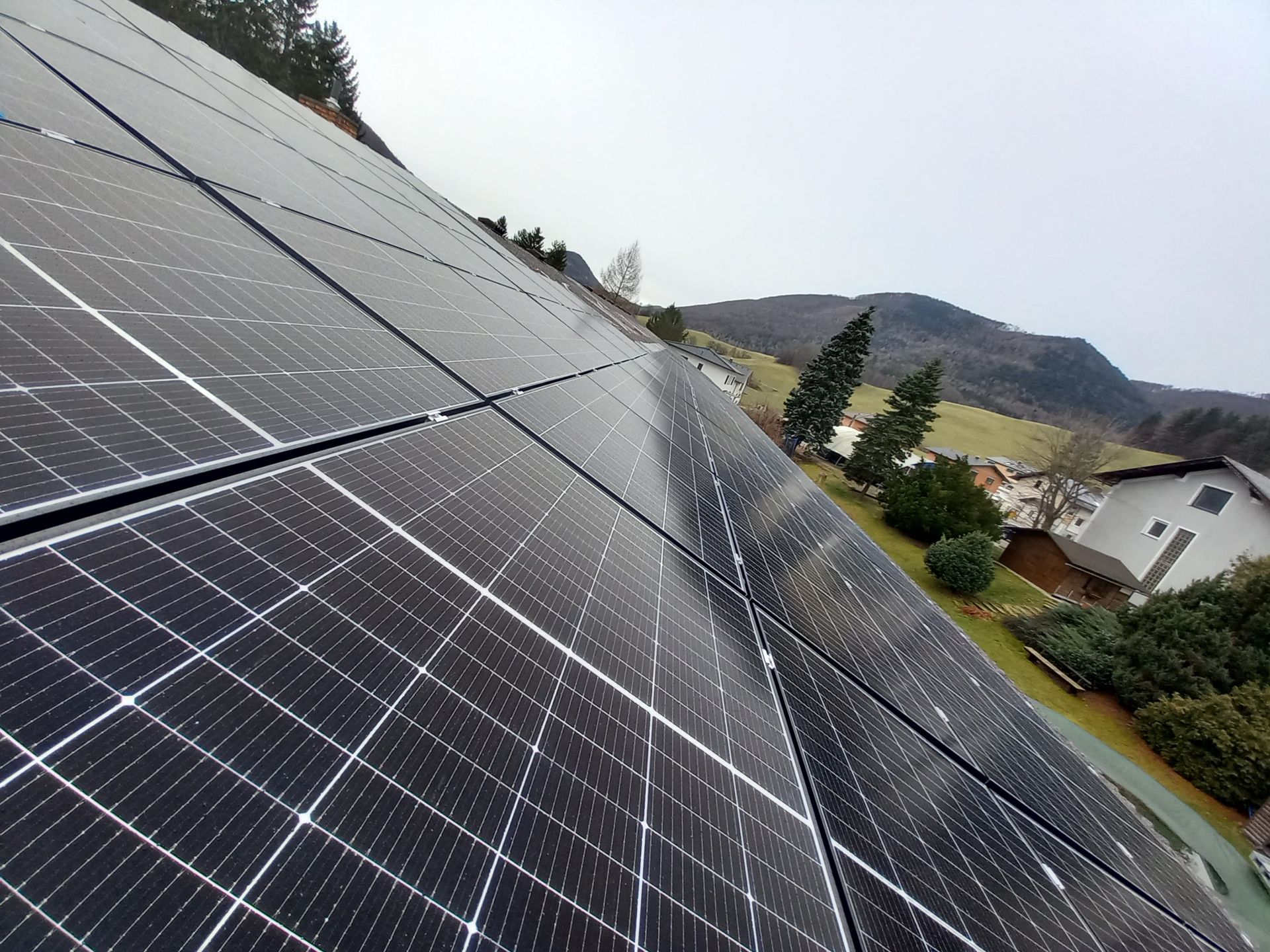 Eine Reihe von Solarmodulen auf einem Dach mit Bergen im Hintergrund