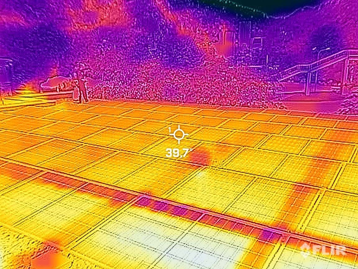 Infrarotbild von Solarmodulen mit Hotspots (gelb), die auf mögliche Probleme hinweisen.