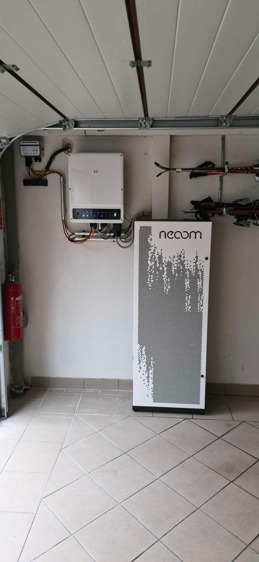 In einer Garage steht ein Stromspeicher neben einem Feuerlöscher.