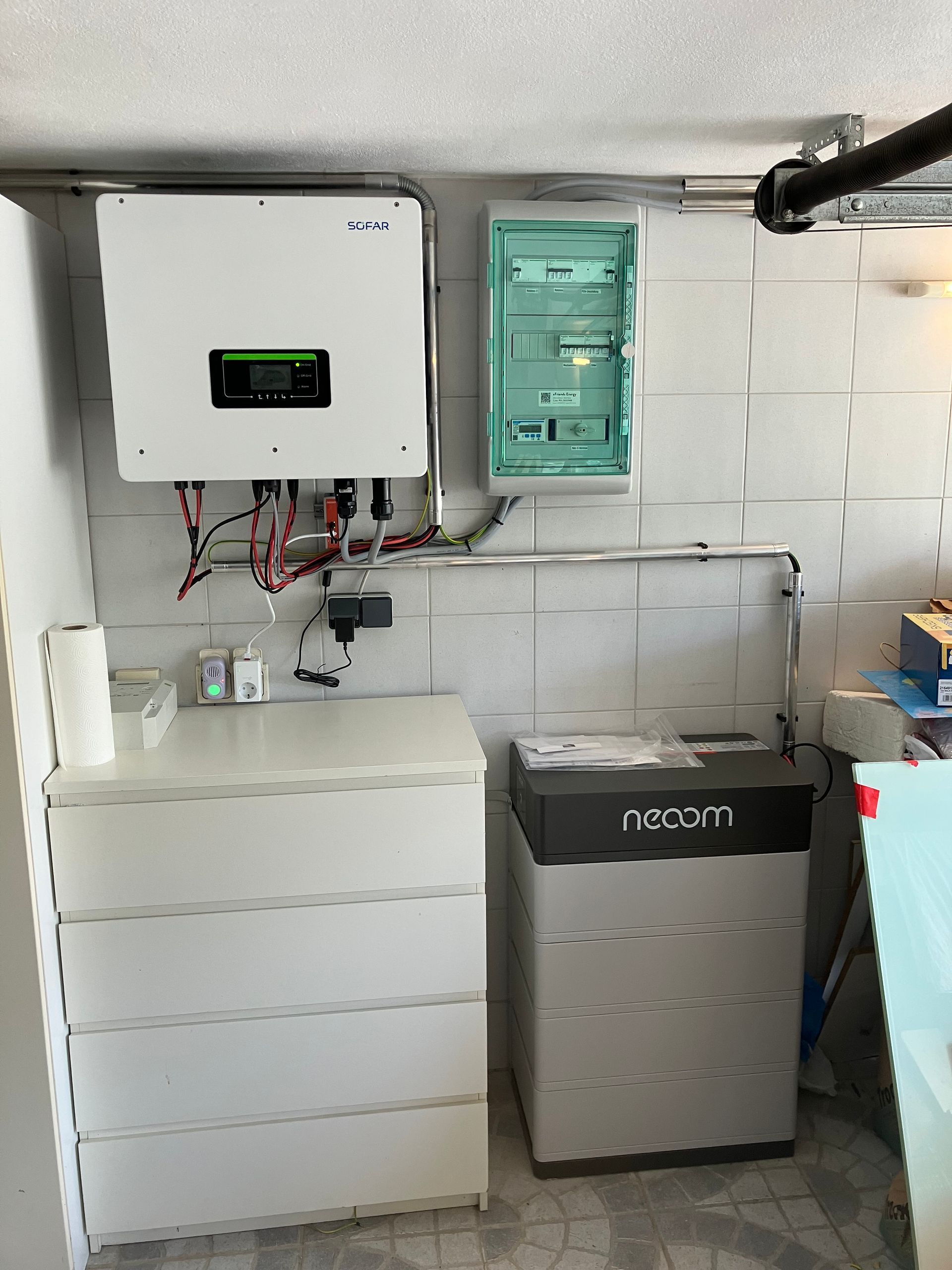 Ein Raum mit einer Kommode, einer Kiste und einem Stromspeicher an der Wand.