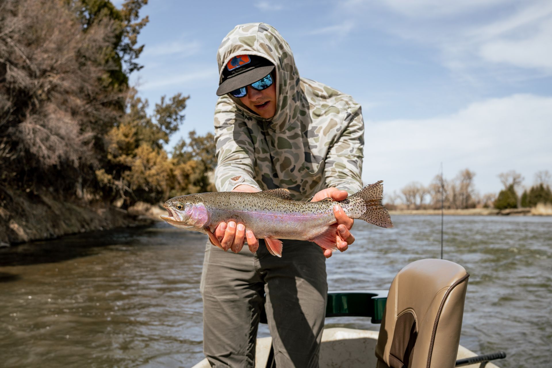 Fisherman holding rainbow trout on the Madison River in Montana