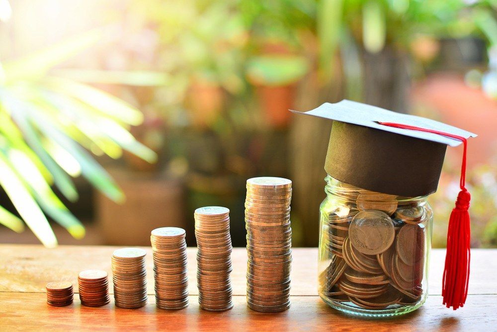 Graduating Jar Of Coins Beside Stacks Of Coins On A Sunlit Table — Goulburn Solar In Goulburn, NSW