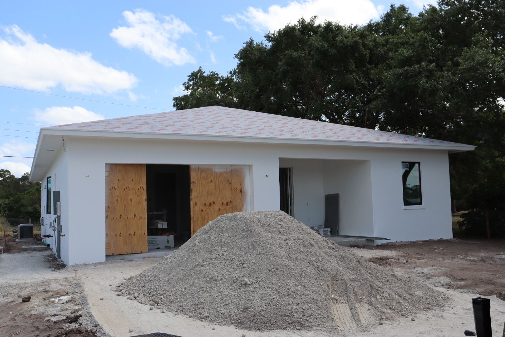 A white house under construction with a pile of gravel in front.