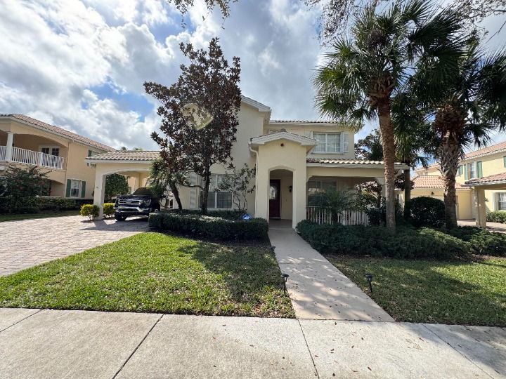 Beige house with green lawn, palm trees, and a walkway.