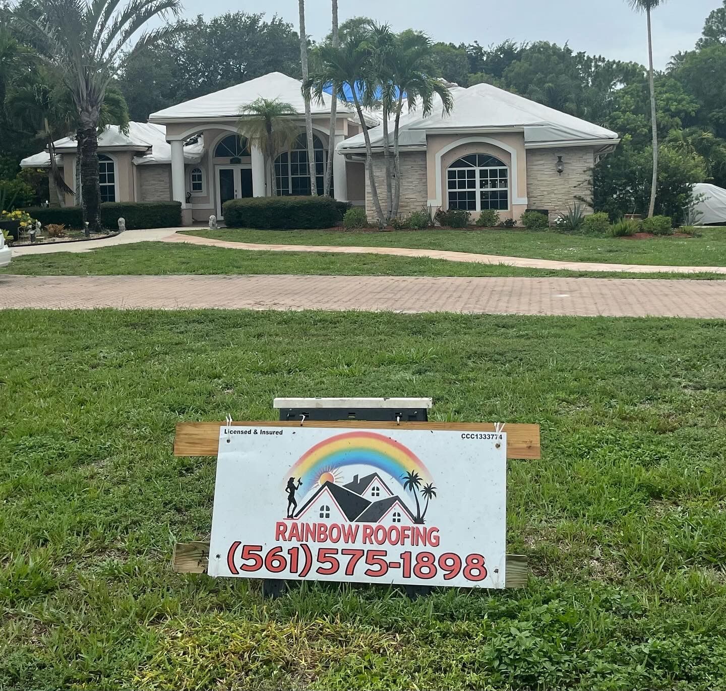 House with Rainbow Roofing sign in front.