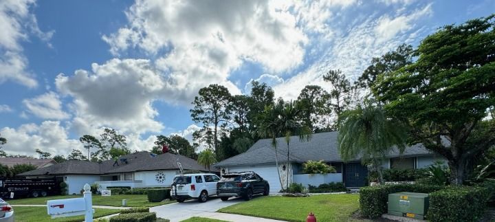 Residential neighborhood with houses, cars, and a blue sky with clouds.