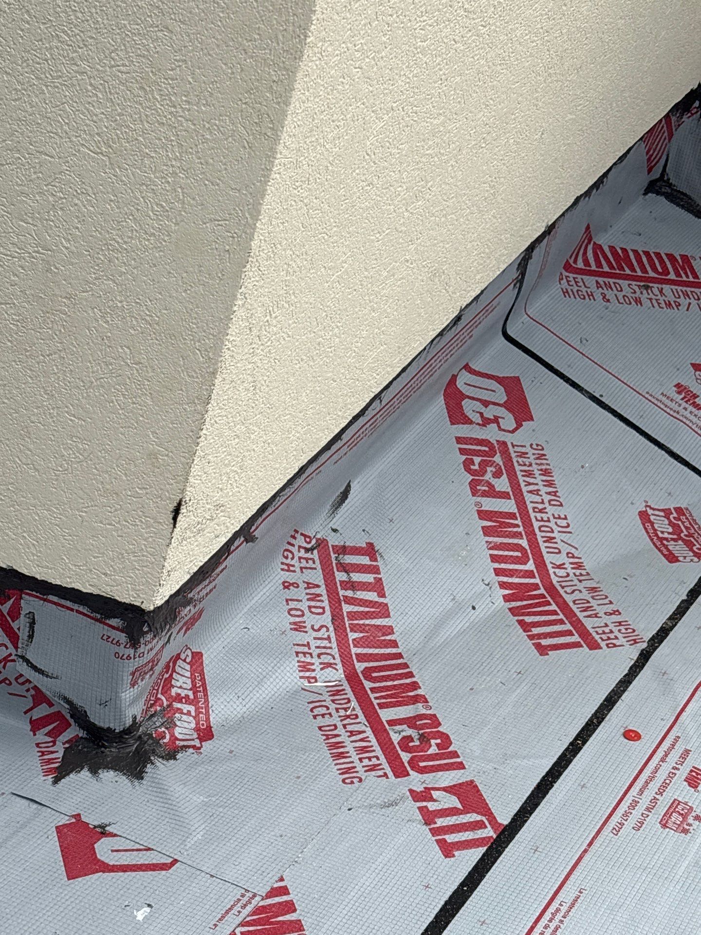 Gray and red Titanium PSU tile roofing under a white angled wall.