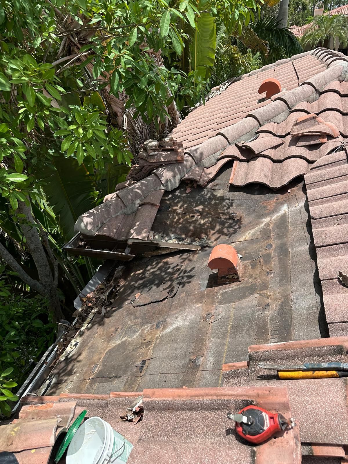 Damaged tile roof section with missing tiles, likely from storm.
