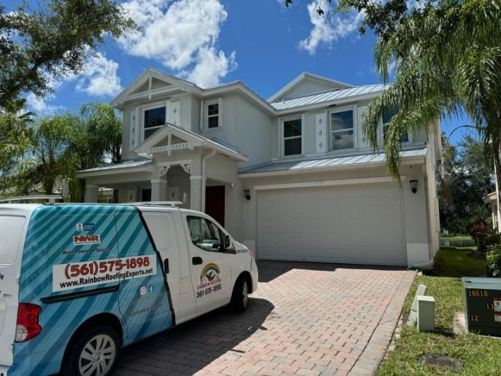 White two-story house with a blue and white van in the driveway.