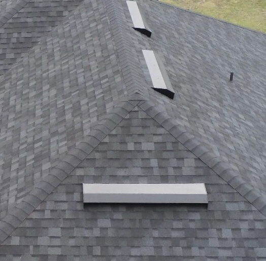 Gray shingle roof with three rectangular vents, viewed from above.