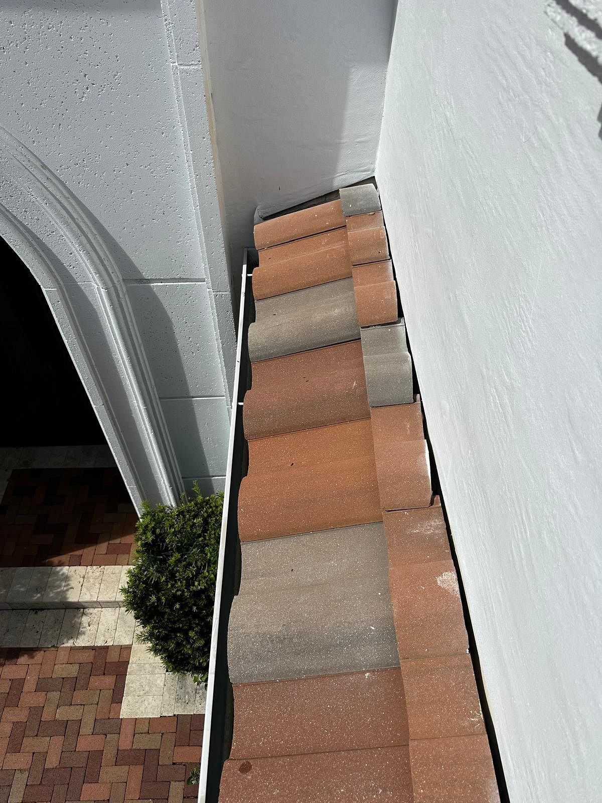 Clay roof tiles, white wall, and a shaded entrance.
