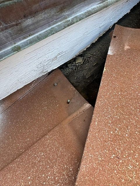 Close-up of brown metal roofing with a gap revealing the underside.