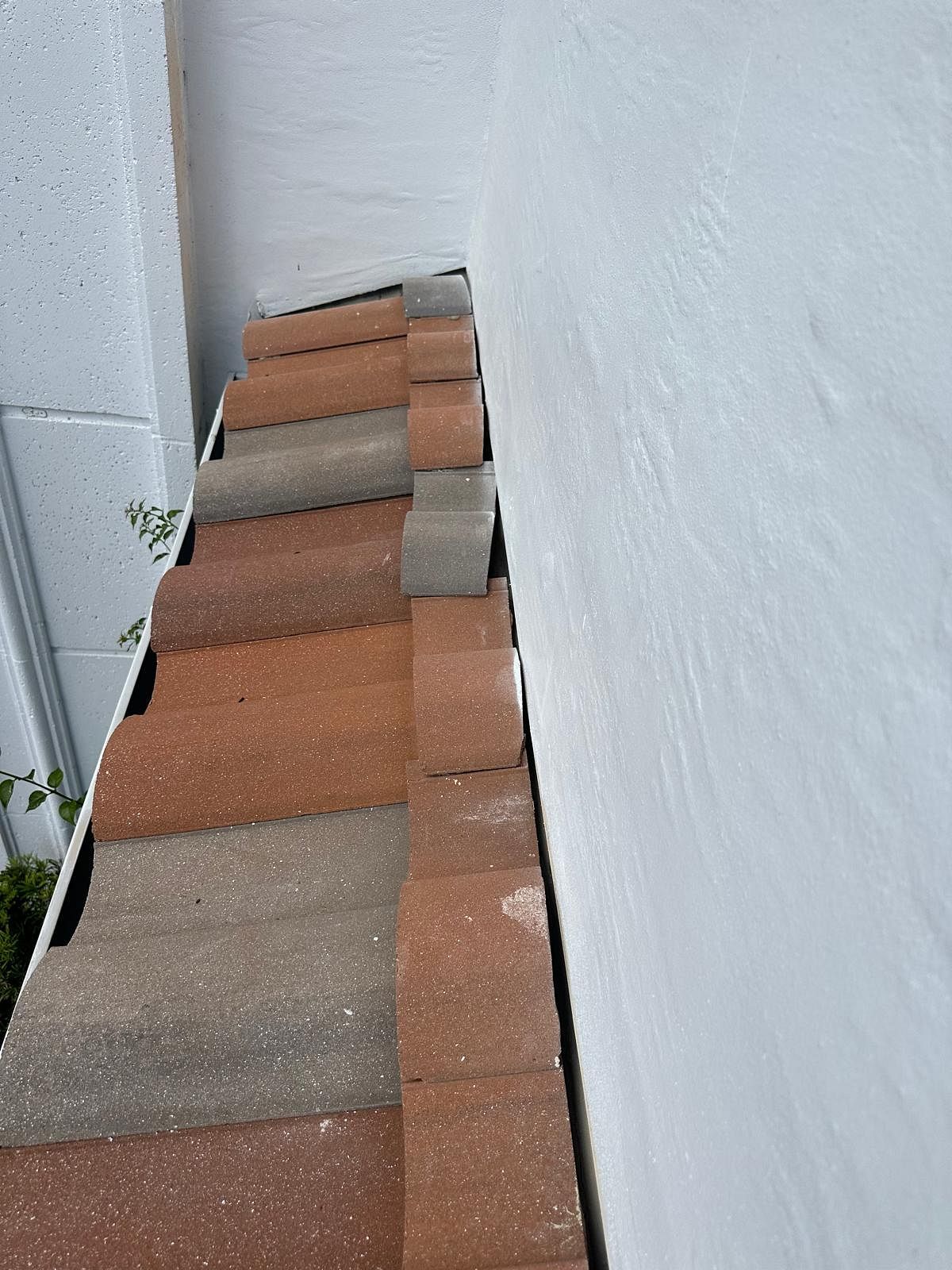 Bricks along a white wall and a corner, likely a roof's edge. Red and gray bricks.