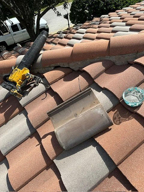 Clay roof with broken tile and tools, sunlight, residential setting.