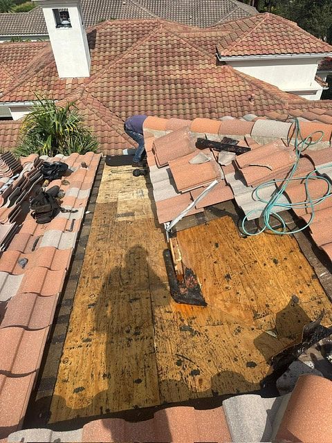 Roofer repairing a section of damaged roof tiles.