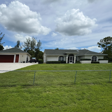 White house with attached garage, green lawn, cloudy sky.