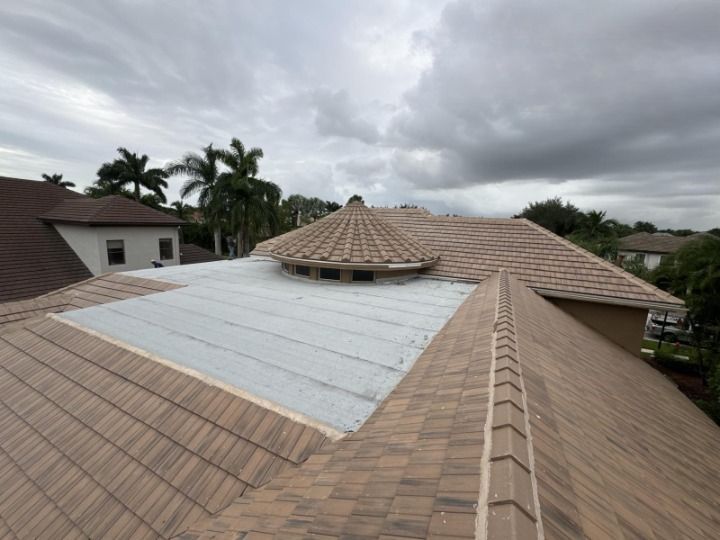 Tiled roof with a round section, patched area, and cloudy sky in a residential setting.