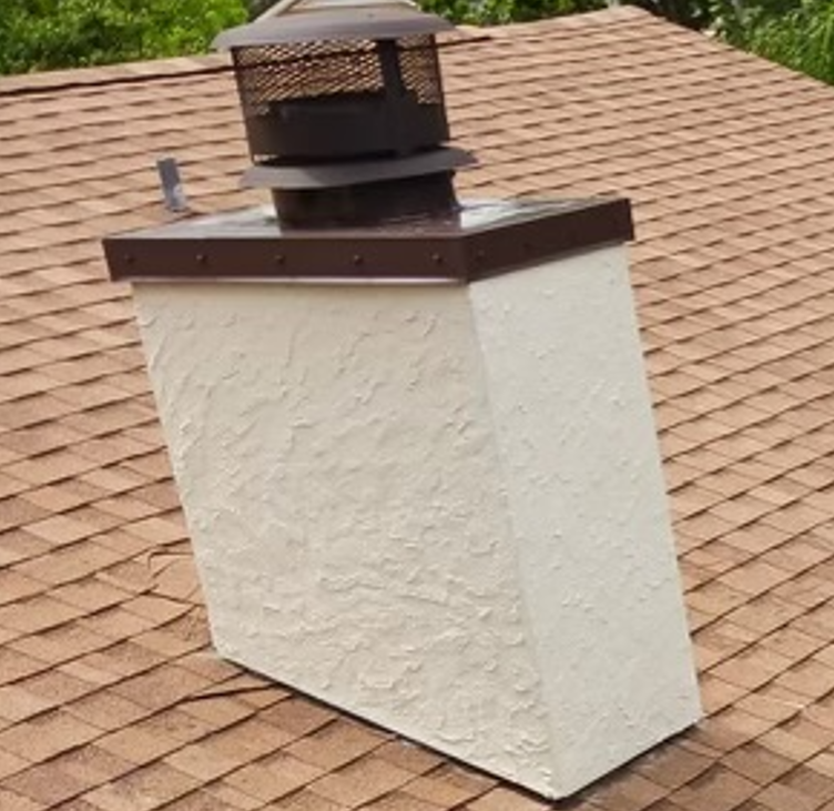 Beige stucco chimney on a shingled roof; brown chimney cap and flashing.