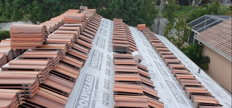 A partially tiled roof with terracotta tiles. Some sections have tiles installed while others only have underlayment.