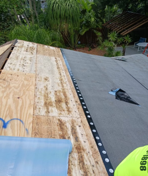 Roof partially covered with plywood, with black felt paper, and flashing being installed.