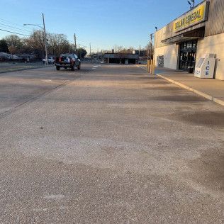 A car drives on a cracked road, beside a Dollar General store.