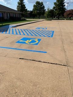 Handicapped parking spaces painted blue and yellow in a concrete parking lot.