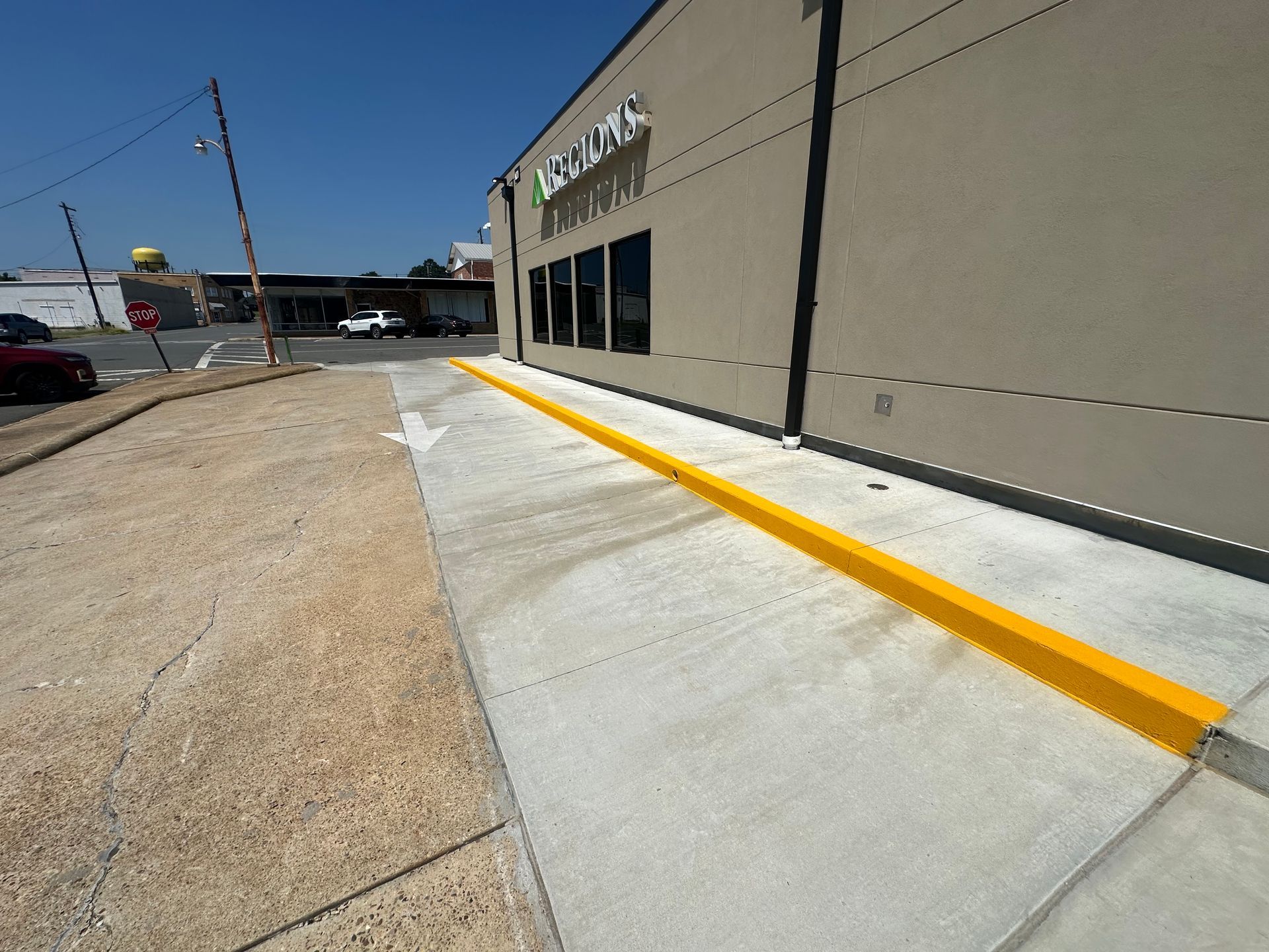 Sidewalk with a yellow curb along a building. Exterior shot on a sunny day.