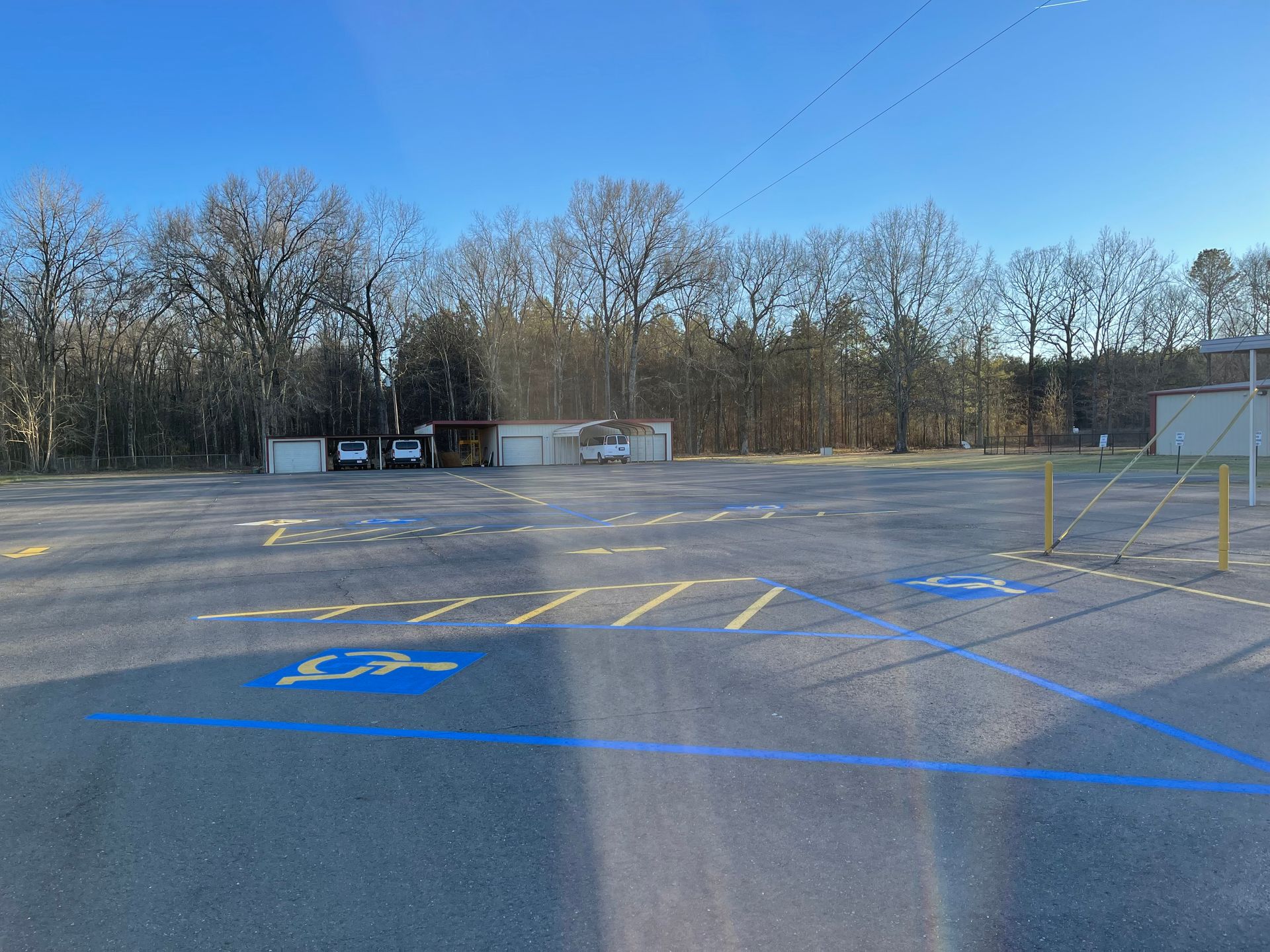 Empty parking lot with handicap spaces; trees in background.