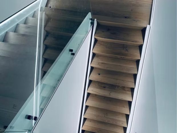 Wooden staircase with glass railing. Interior shot, overhead view.