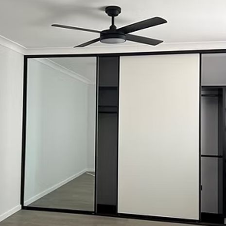 Sliding closet doors: one mirror, one white panel, black frames. Ceiling fan.
