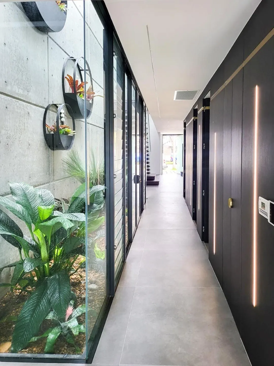 Green laser level projecting lines across a hallway with white walls and a wooden floor.