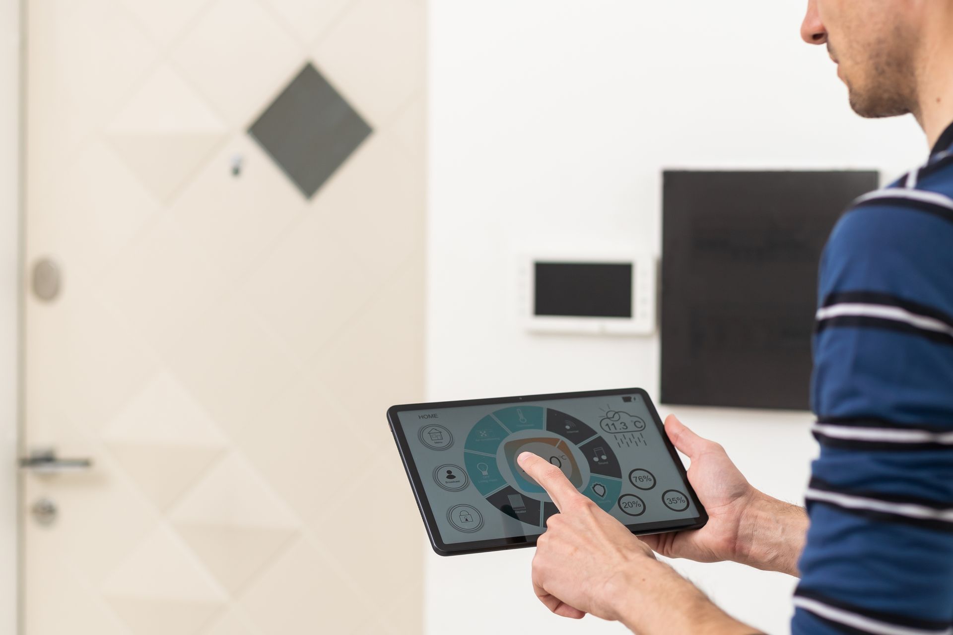 Person answering a video call on a screen, next to an outdoor intercom. Both touch screens are being used.