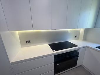Bedroom with gray walls, white bedding, tan bench, dark ceiling fan and round mirror.