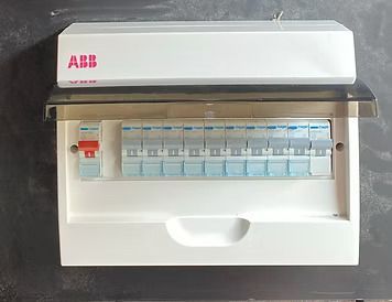 White ABB electrical breaker panel with multiple switches, mounted on a dark surface.