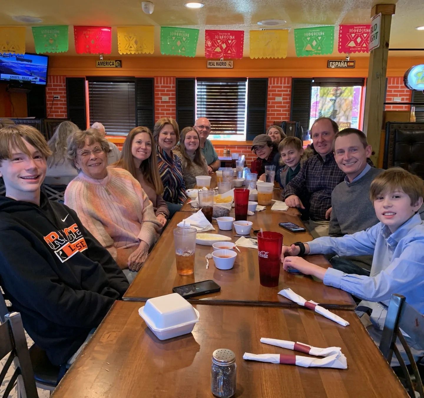 A group sits at tables in a brightly decorated restaurant, smiling as they gather for a meal.