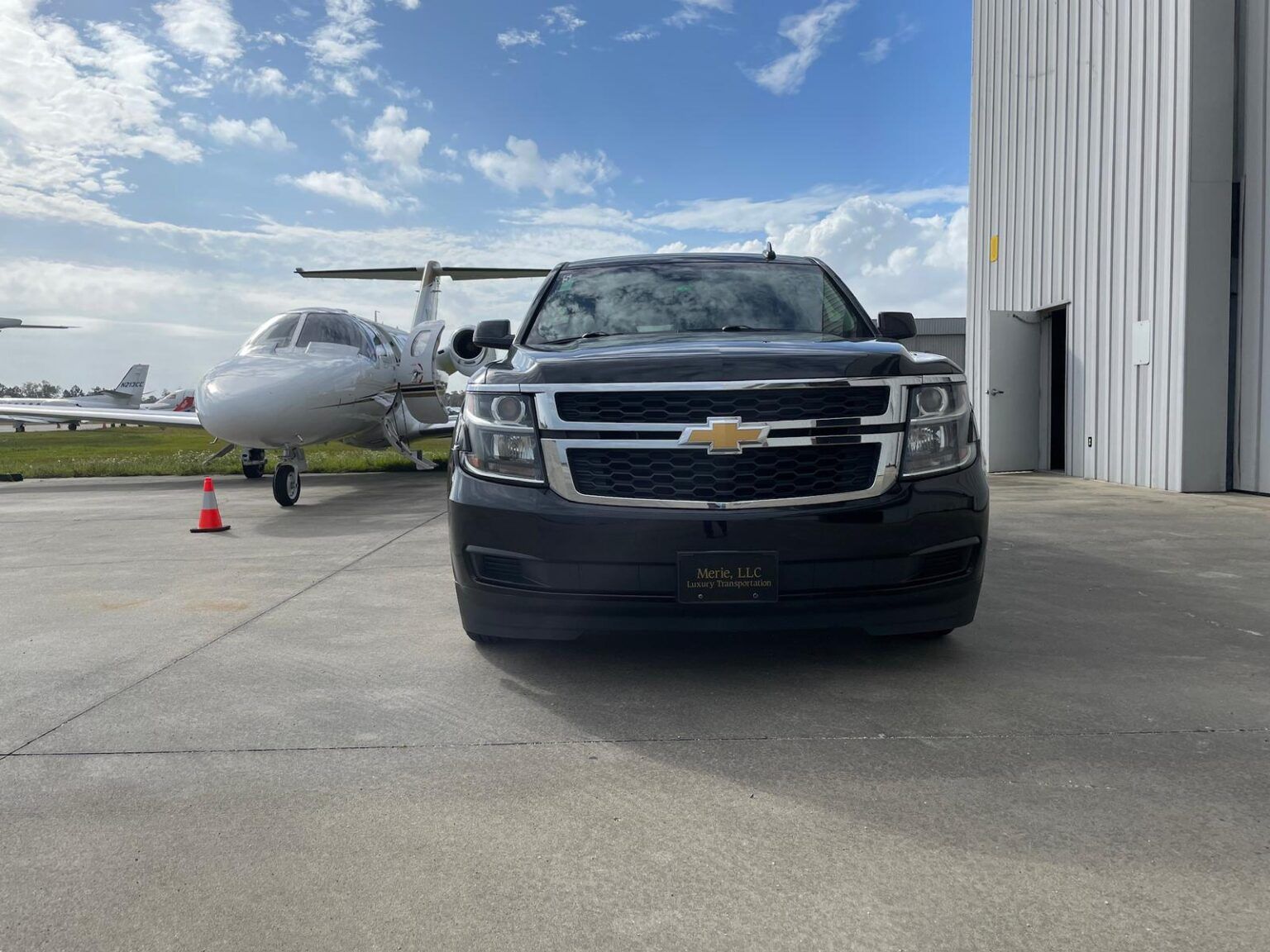 A chevrolet suburban is parked in front of a private jet.