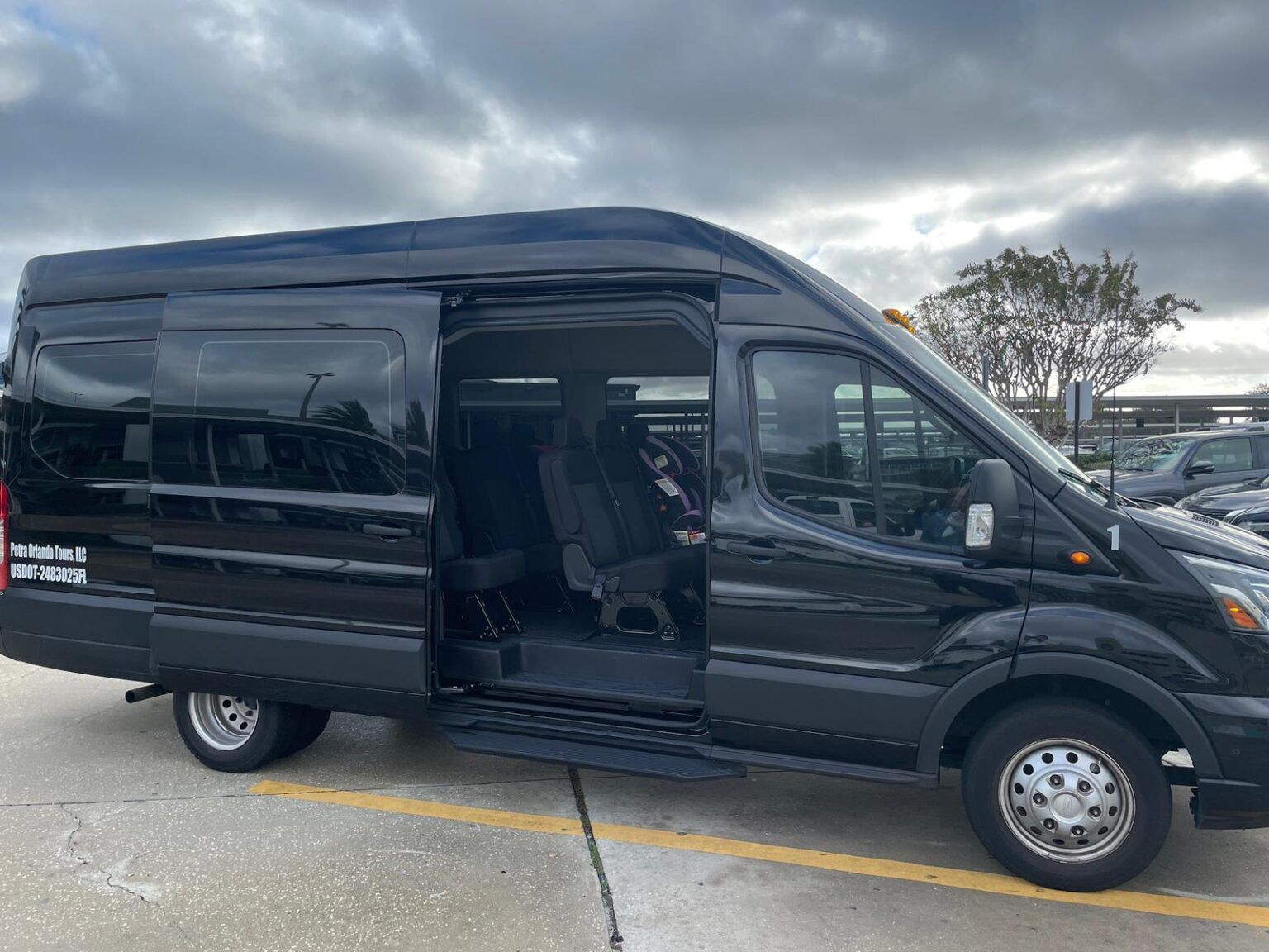A black van is parked in a parking lot with the door open.