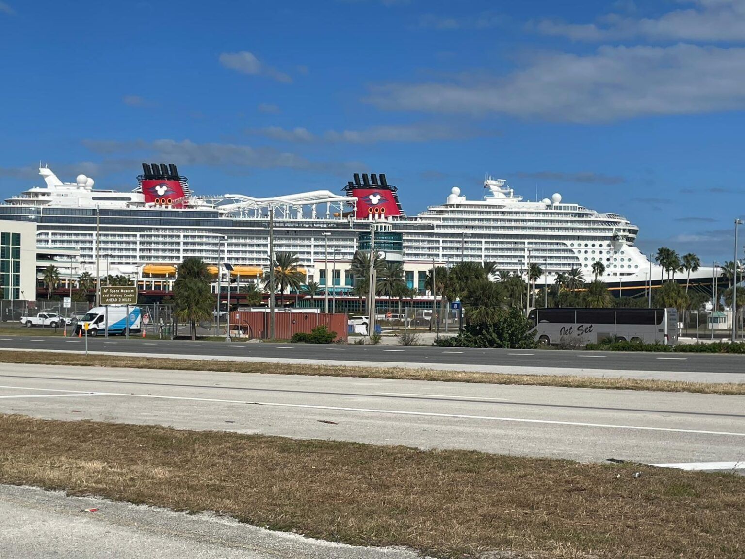 Two cruise ships are docked in a harbor on a sunny day