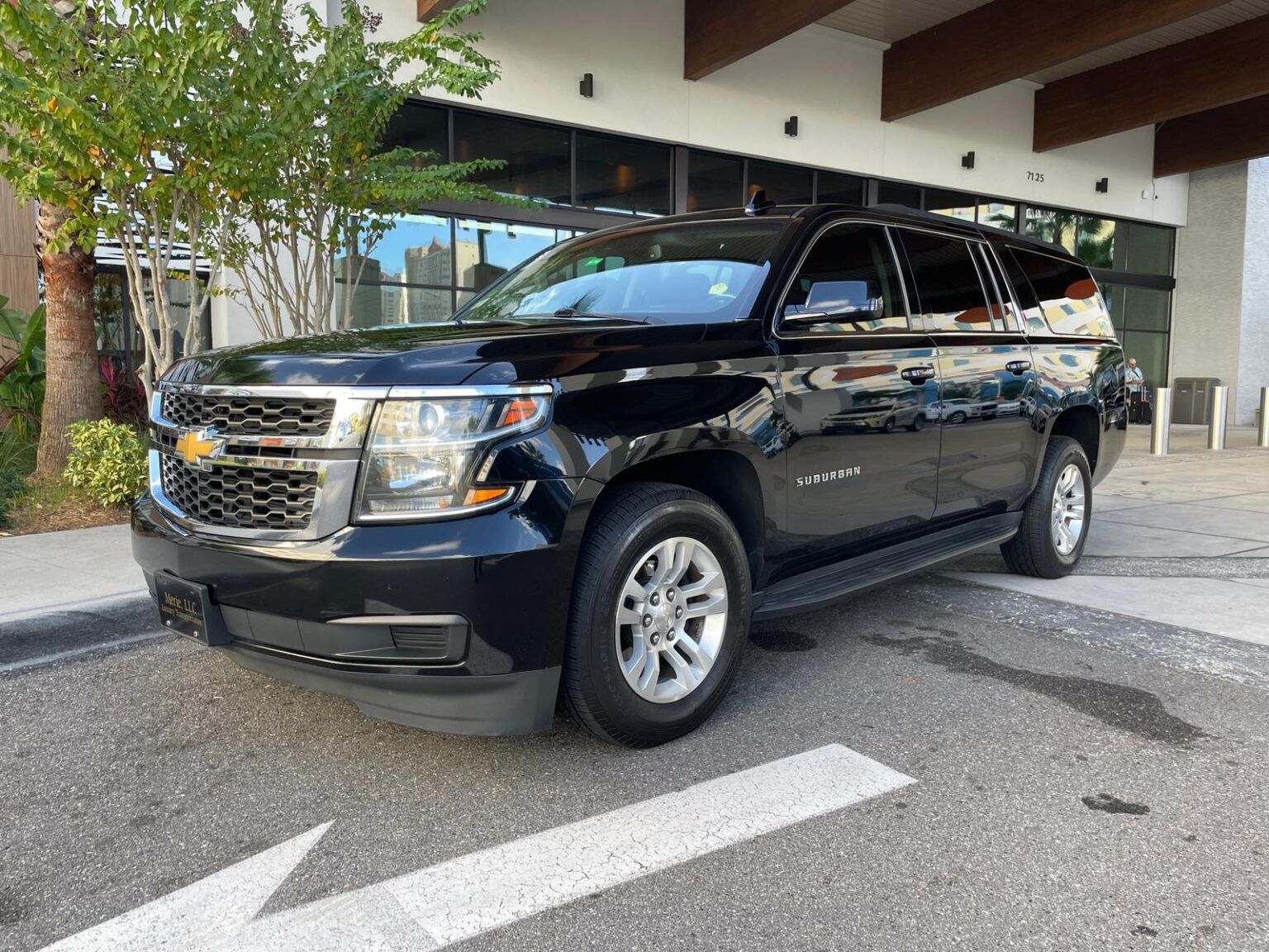 A black chevrolet suburban suv is parked in front of a building.