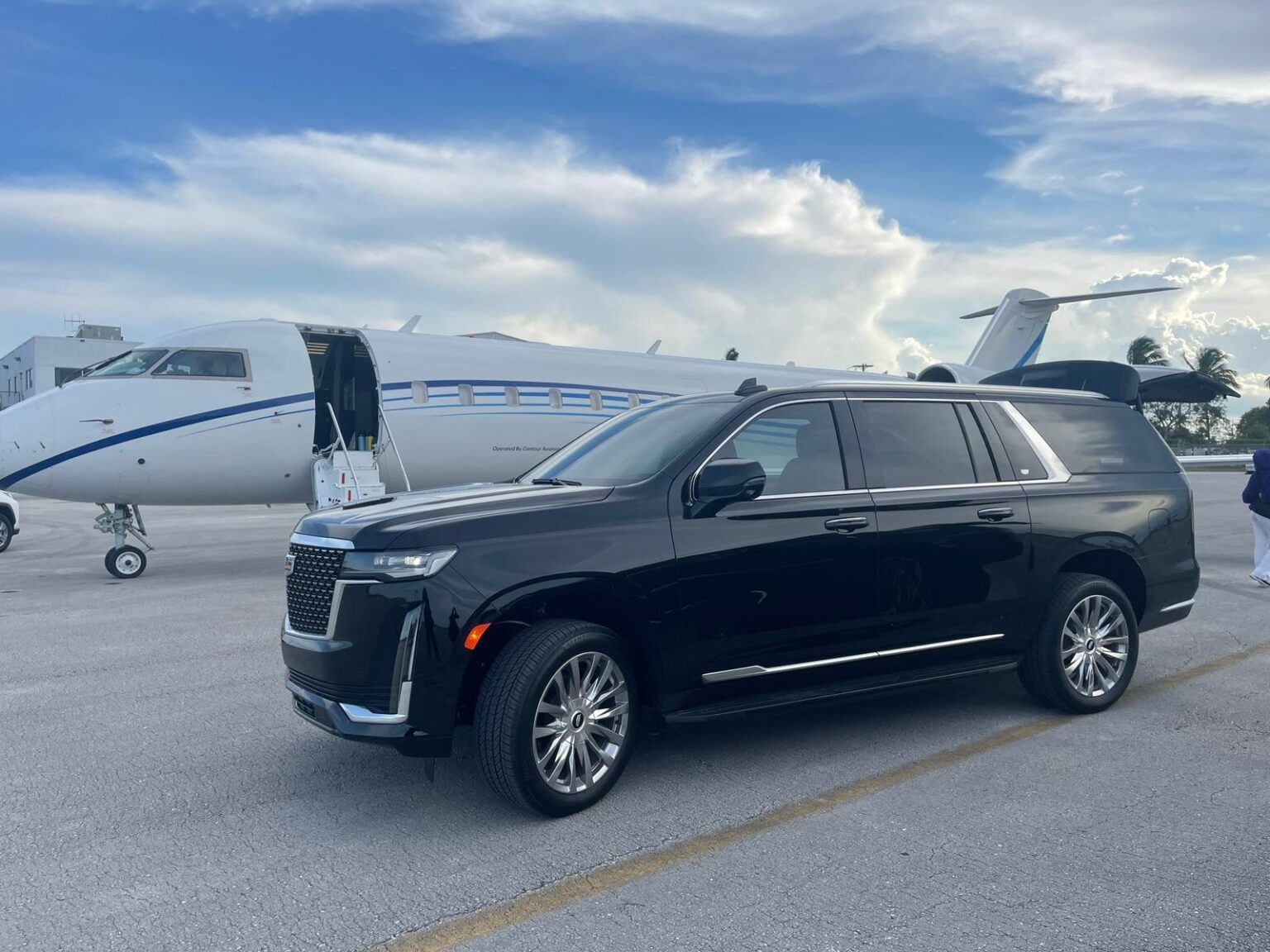 A black suv is parked in front of a private jet.