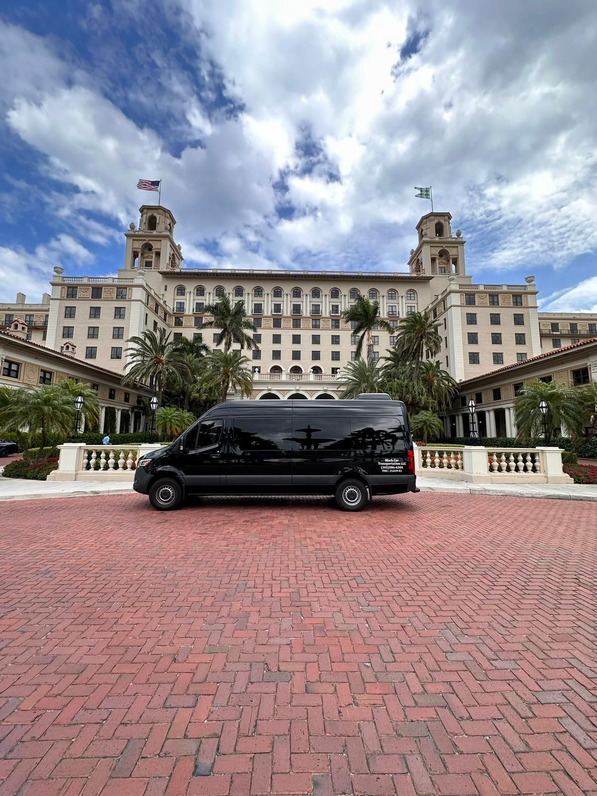 A black van is parked in front of a large building.