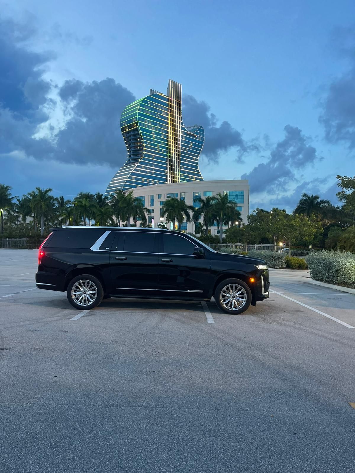 A black suv is parked in a parking lot in front of a large building